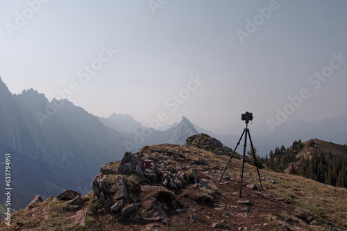 Views of mountains and forests on a summers day in Kananaskis Country, Alberta, Canada from on top of King Creek Ridge with a vintage film camera on a tripod in frame
