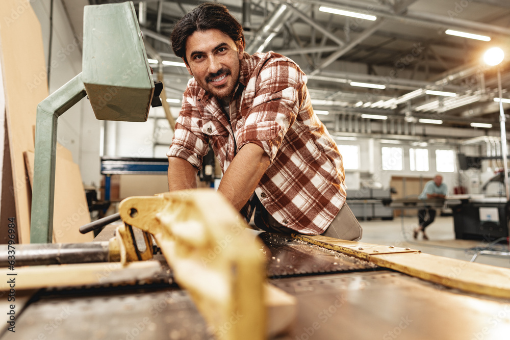 Young carpenter working on woodworking machines in the furniture factory Young carpenter working on woodworking machines in the furniture factory
