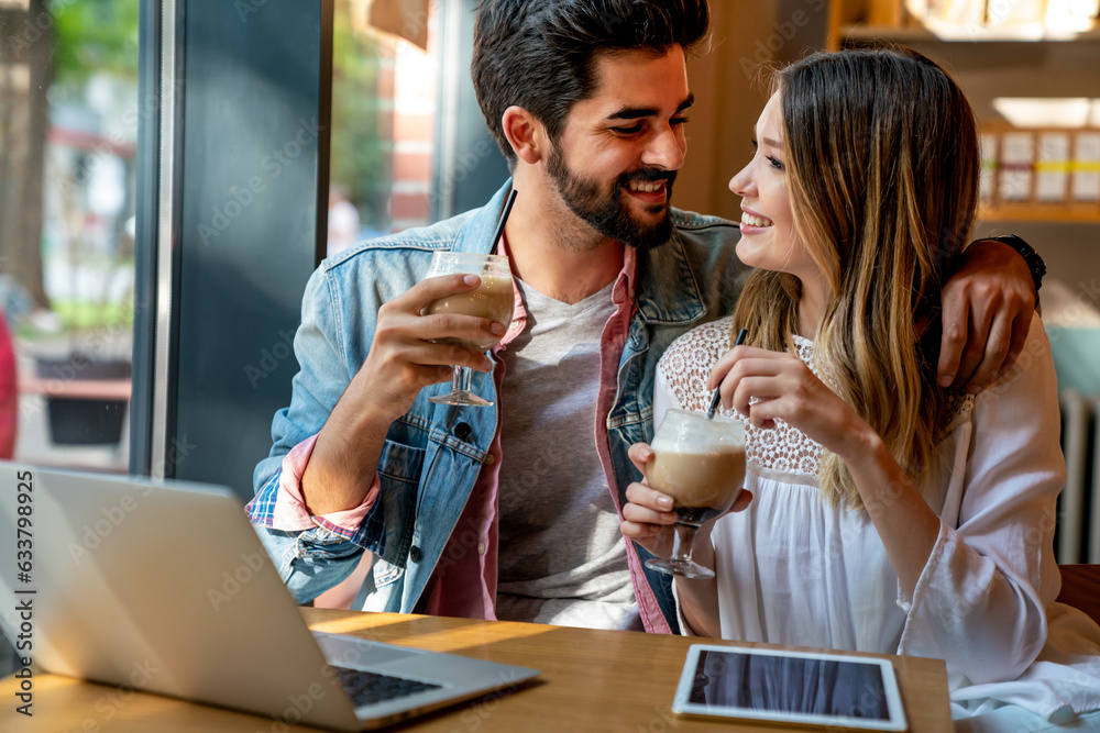Couple sitting at cafe smiling, using laptop, spending time with pleasure, drinking coffee. Couple sitting at cafe smiling, using laptop, spending time with pleasure, drinking coffee.