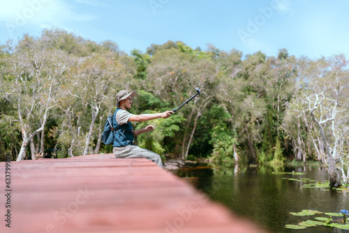 Asian man sitting and traveling on a bridge Take fun photos and videos. Rivers and mangroves
