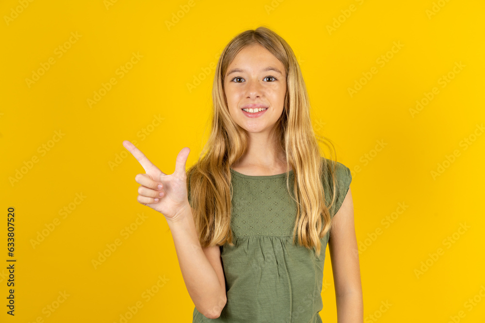 blonde kid girl wearing green T-shirt over yellow studio background pointing up with fingers number eight in Chinese sign language BÄ. blonde kid girl wearing green T-shirt over yellow studio background pointing up with fingers number eight in Chinese sign language BÄ.