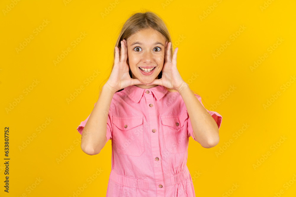 young beautiful blonde kid girl over yellow studio background Pleasant looking cheerful, Happy reaction young beautiful blonde kid girl over yellow studio background Pleasant looking cheerful, Happy reaction