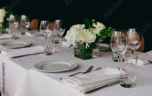 vue sur une table blanche avec assiettes et fourchettes ainsi qu'un centre de table aux fleurs blanches