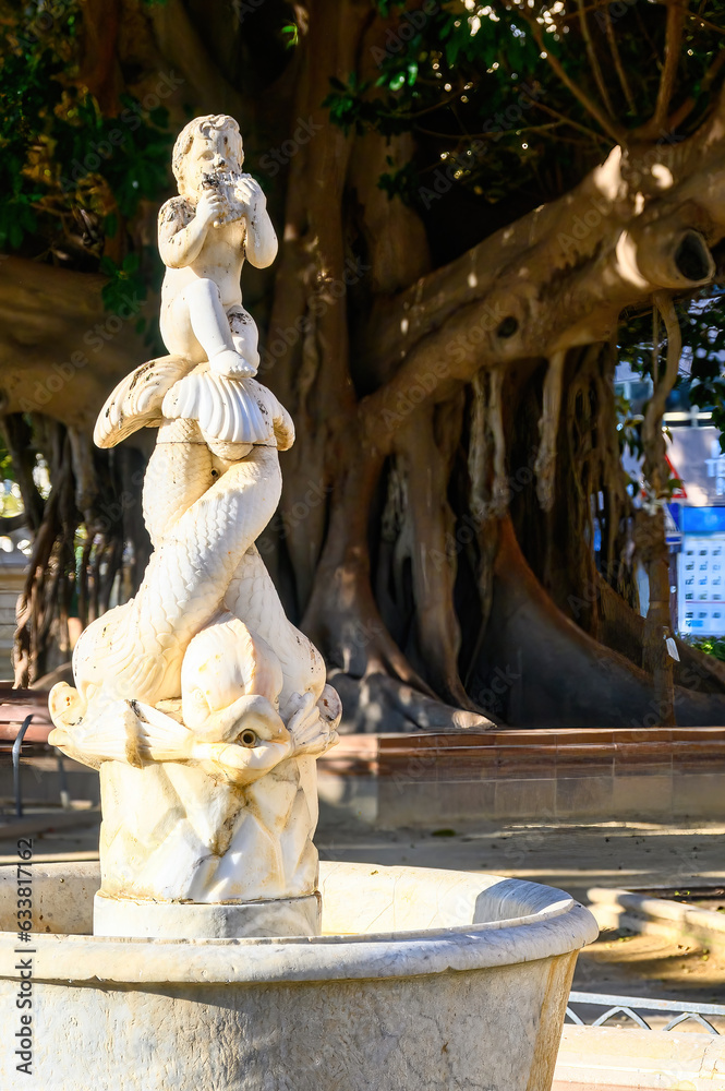Alicante, Spain,  Ancient sculpture in a fountain named El Nino Flautista. The marble structure is located in Canalejas Park (1886) in the city's waterfront district.