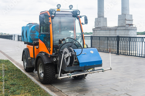 small tank truck for cleaning paths and watering plants on the city embankment photo