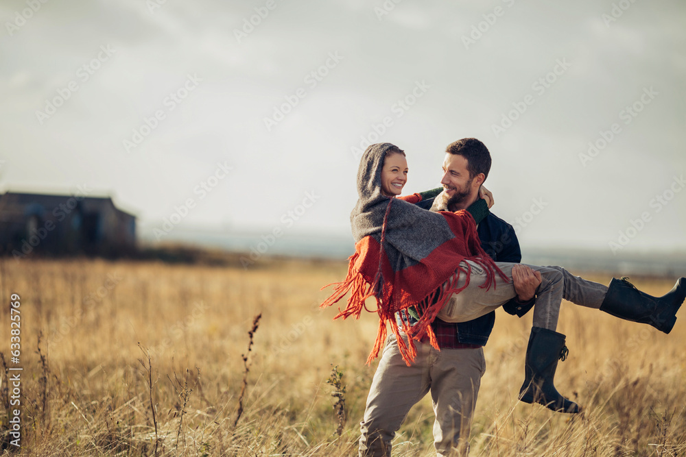 Young man carrying his girlfriend on a field in the countryside Young man carrying his girlfriend on a field in the countryside