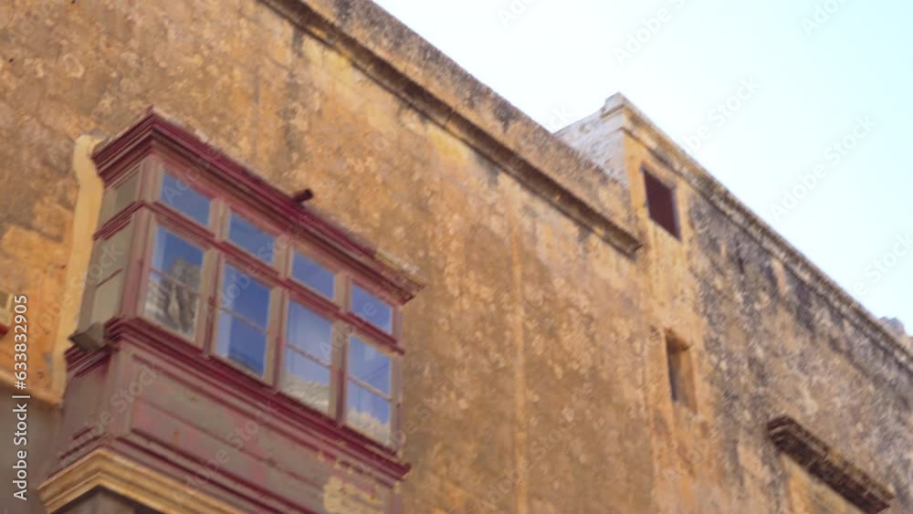 Mdina, Malta POV day low angle pan to limestone low-rise buildings with traditional lantern and balconies inside the medieval Silent City citadel. Mdina, Malta POV day low angle pan to limestone low-rise buildings with traditional lantern and balconies inside the medieval Silent City citadel.