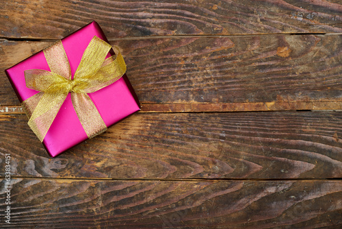 pink gift box with golden ribbon on wood table. flat lay