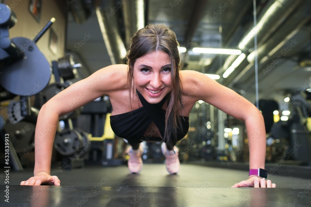 Portrait of fit strong muscle young happy woman in a good shape training in a gym, fitness centre