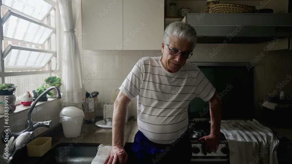 Worried senior man standing in home kitchen ruminating thoughts and past memories feeling regret and remorse Worried senior man standing in home kitchen ruminating thoughts and past memories feeling regret and remorse
