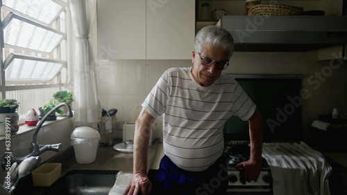 Foto Worried senior man standing in home kitchen ruminating thoughts and past memorie