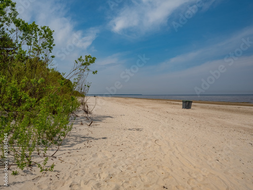 Dumpster on sand beach of Baltic sea in Jurmala, Latvia. Green trees. Blue sky. Sunny summer day.