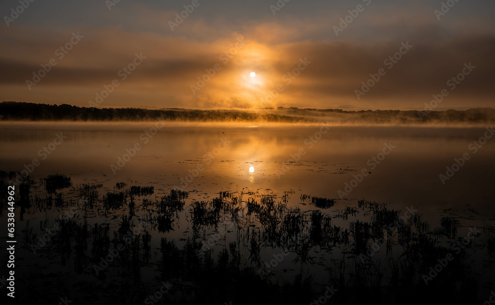 sunrise in the middle of the mountains with a orange sun, and lake with blue water. Cloudy morning sunrise in the middle of the mountains with a orange sun, and lake with blue water. Cloudy morning
