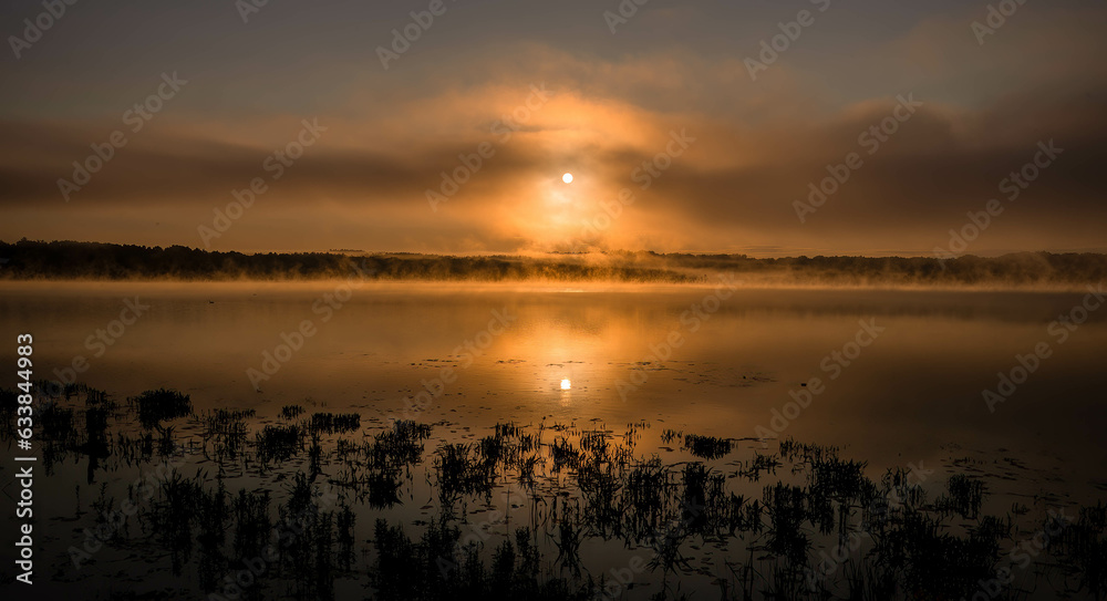 sunrise in the middle of the mountains with a orange sun, and lake with blue water. Cloudy morning sunrise in the middle of the mountains with a orange sun, and lake with blue water. Cloudy morning