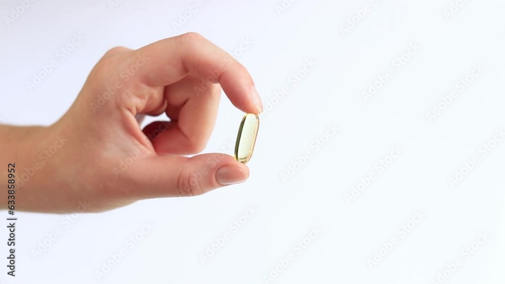 Medicine capsule in female hands, Omega-3. Bright yellow transparent vitamins on a white background. Medicine and healthcare. Vitamins and dietary supplements. Omega 3 Gold Fish Oil Capsule Medicine capsule in female hands, Omega-3. Bright yellow transparent vitamins on a white background. Medicine and healthcare. Vitamins and dietary supplements. Omega 3 Gold Fish Oil Capsule