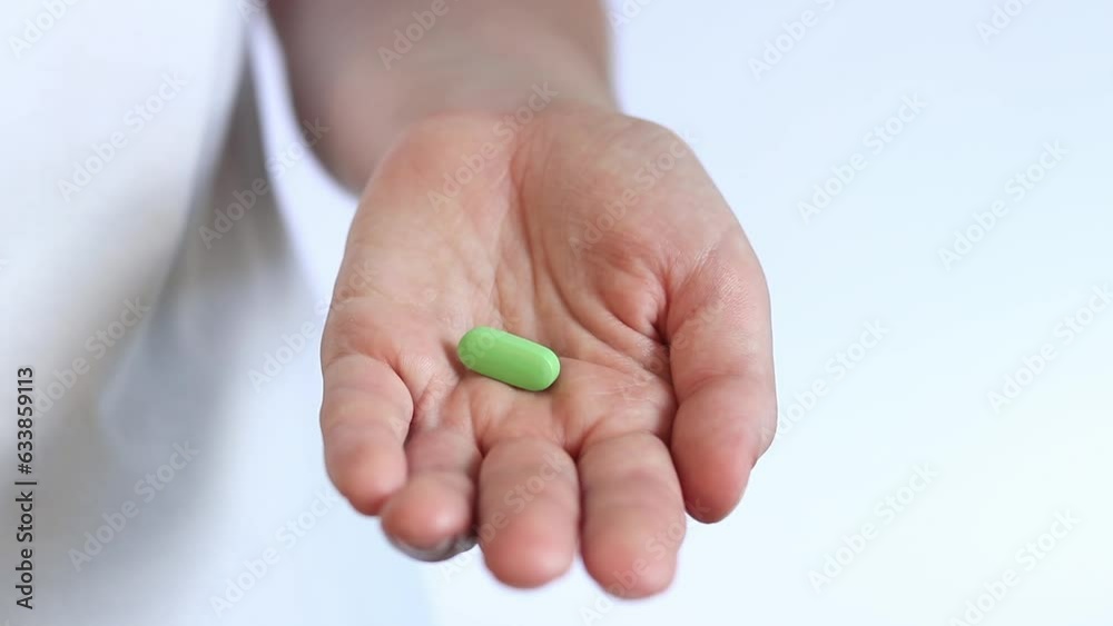 Pour the green tablets from the white bottle into your hand. Vitamins and dietary supplements close-up. Daily dose of vitamins. Pharmaceuticals and drug abuse Pour the green tablets from the white bottle into your hand. Vitamins and dietary supplements close-up. Daily dose of vitamins. Pharmaceuticals and drug abuse