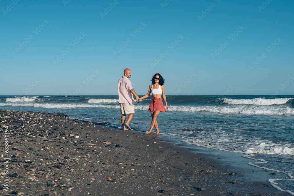 beautiful married couple walking on the sand on the seashore on the beach, husband and wife walking holding hands, love wedding vacation vacation honeymoon trip