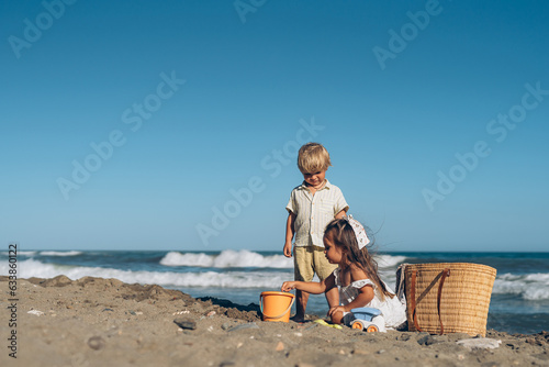 a little boy and a girl of three years old play in the sand on the beach near the sea