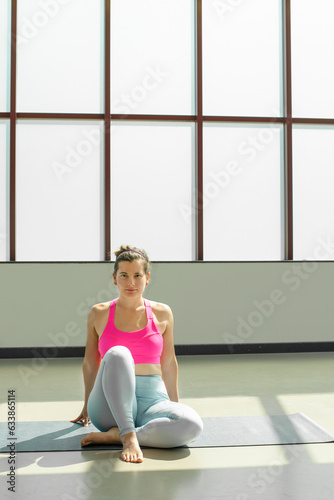 Female trainer doing yoga pose in a yoga class studio. Side view athletic woman performing different yoga poses in studio.