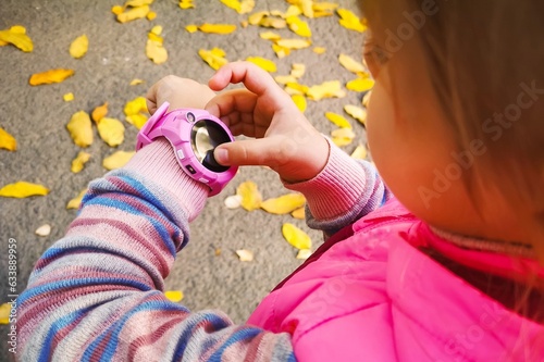 Pink smart watch on the hand of a little girl. The child can call the parents in case of danger. Child safety. Communication with friends. The latest technology.