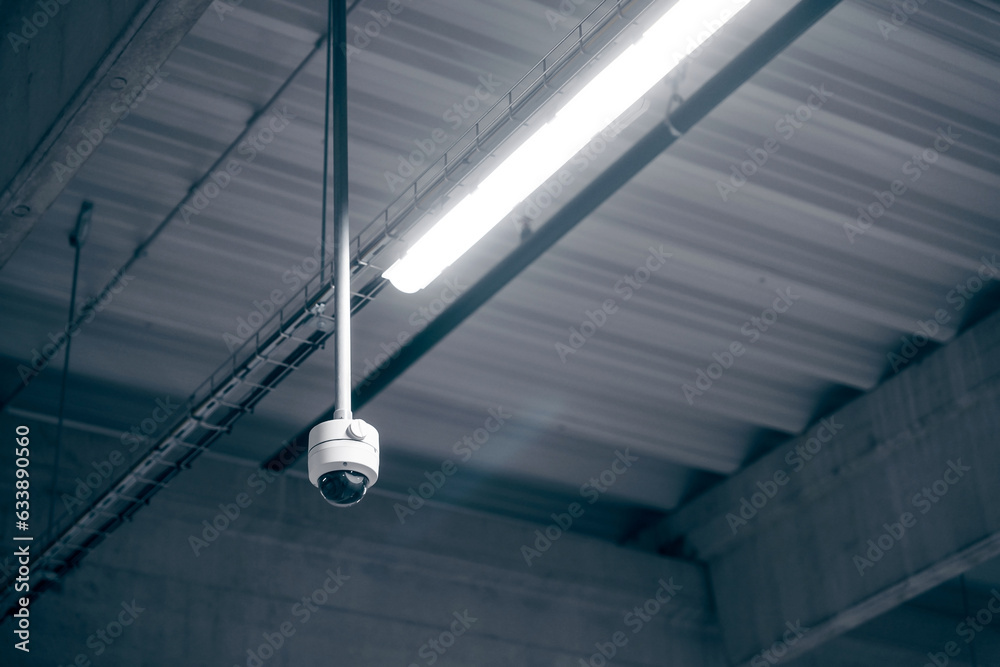 Digital surveillance camera on the ceiling in a warehouse room - obrazy, fototapety, plakaty 