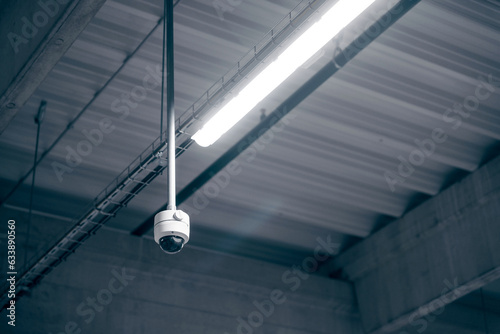 Digital surveillance camera on the ceiling in a warehouse room