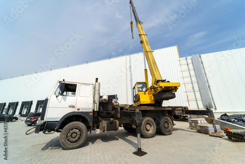 Crane truck against the background of a large warehouse