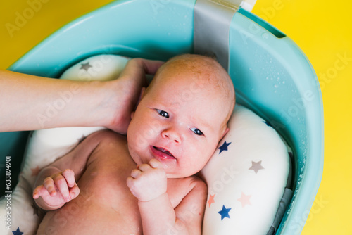 A newborn baby takes a bath on a yellow background. A lovely child is undergoing military training for the first time. The concept of children and hygiene