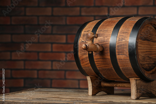 Wooden barrel with tap on table near brick wall, space for text