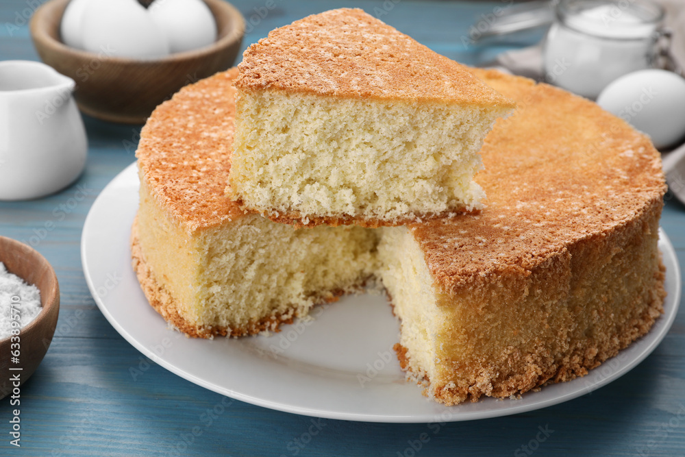 Tasty sponge cake and ingredients on light blue wooden table, closeup Tasty sponge cake and ingredients on light blue wooden table, closeup