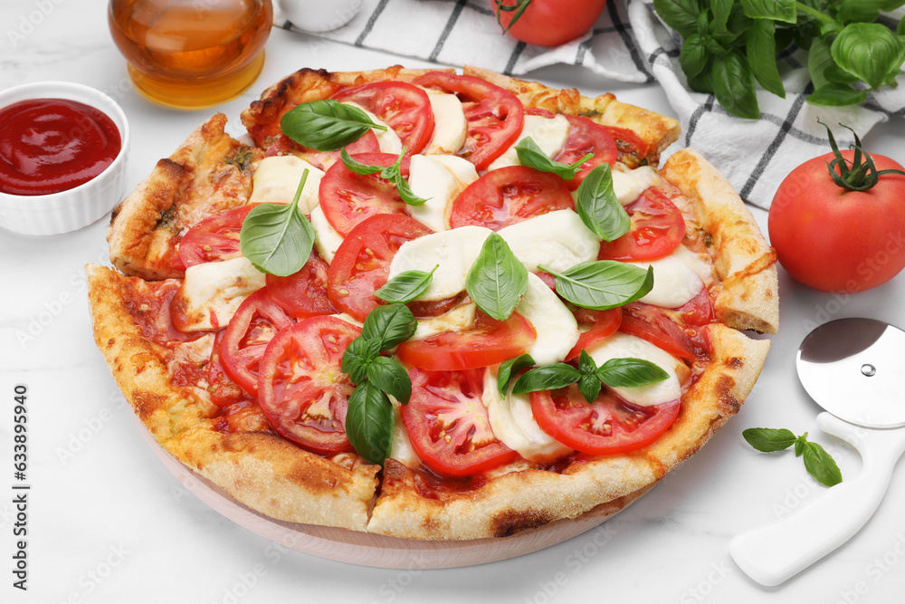 Delicious Caprese pizza with tomatoes, mozzarella and basil served on white marble table, closeup