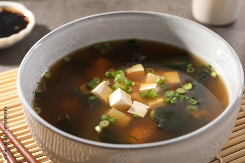 Bowl of delicious miso soup with tofu on bamboo mat, closeup