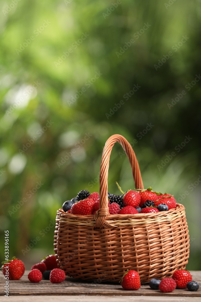 Wicker basket with different fresh ripe berries on wooden table outdoors Wicker basket with different fresh ripe berries on wooden table outdoors