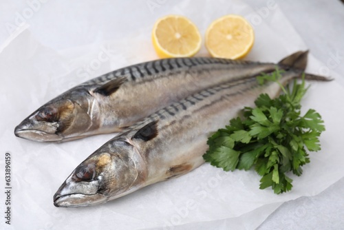 Tasty salted mackerels, parsley and cut lemons on white table, closeup