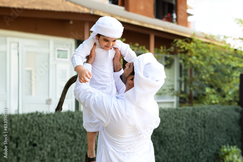 happy family spending time together. Arabian father and his son playing both wearing Kandura dish dash. Arab man with Arabian kid
