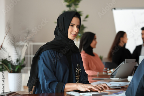Woman in Hijab Abaya at indoor place ideal for corporate office or University campus concept.  Arab female woman with colleagues or classmates. 