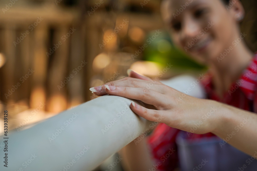 Obraz premium Closeup young female leather goods maker looking and touch leather roll for make products in workshop.
