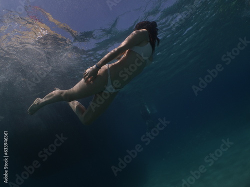 lady swims underwater with bikini sun beams and rays
