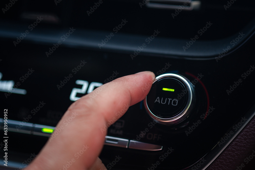 The driver controls the air conditioning in a modern electric car. Detail with the air conditioning button inside a car.