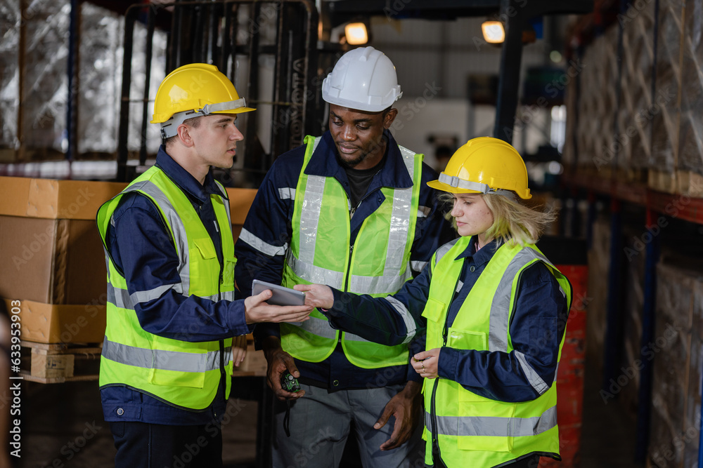 Group of warehouse employees using a digital warehouse management system. logistics manager using a digital tablet while having a meeting with his team. Group of warehouse employees using a digital warehouse management system. logistics manager using a digital tablet while having a meeting with his team.