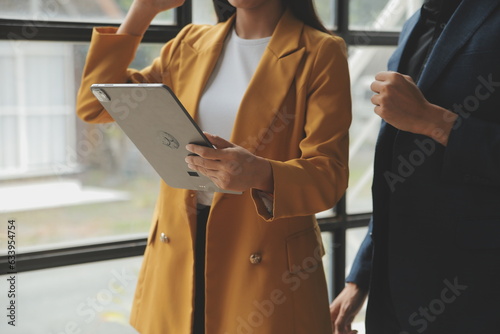 Entrepreneur Asian businessman and businesswoman discussing new business project in tablet in modern Meeting In Modern Office, Asian business casual concept.