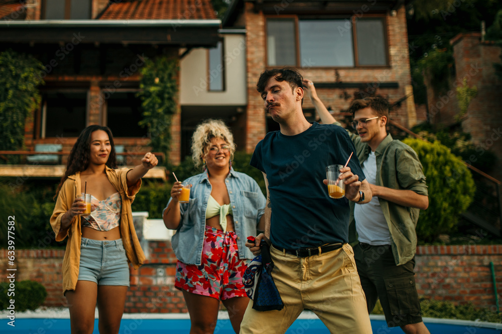 Fototapeta premium Happy friends dancing and enjoying pool party at poolside.