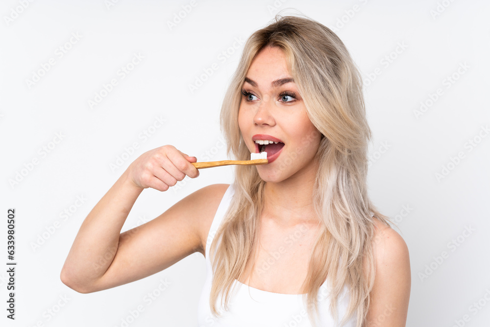 Teenager blonde girl over isolated white background with a toothbrush Teenager blonde girl over isolated white background with a toothbrush