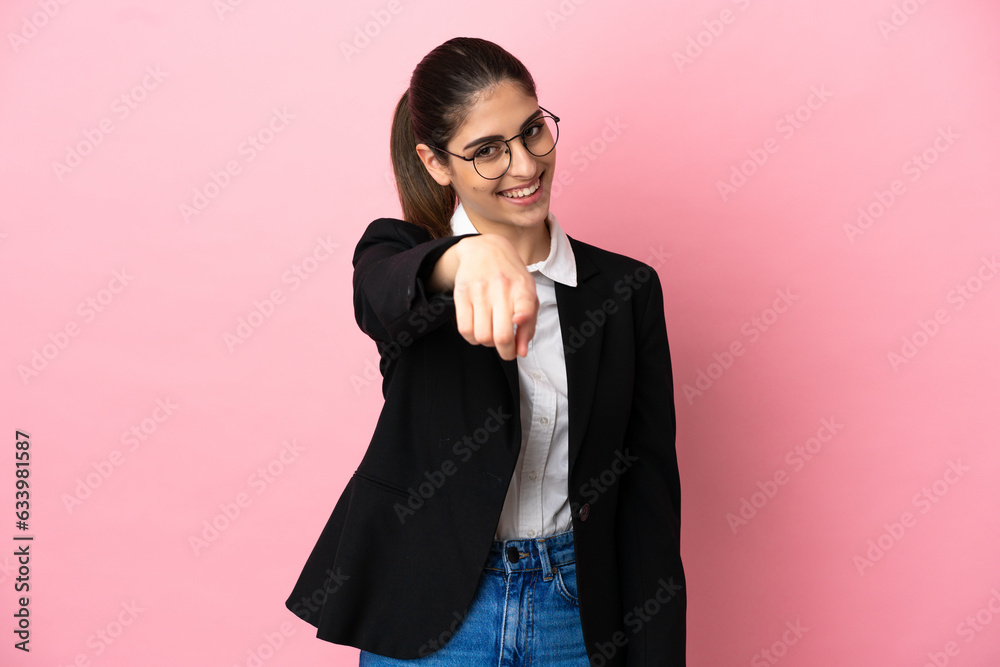 Young caucasian business woman isolated on pink background points finger at you with a confident expression Young caucasian business woman isolated on pink background points finger at you with a confident expression