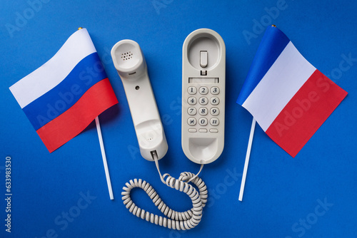 An old telephone and two flags on a blue background, a concept on the topic of telephone conversations between France and Russia