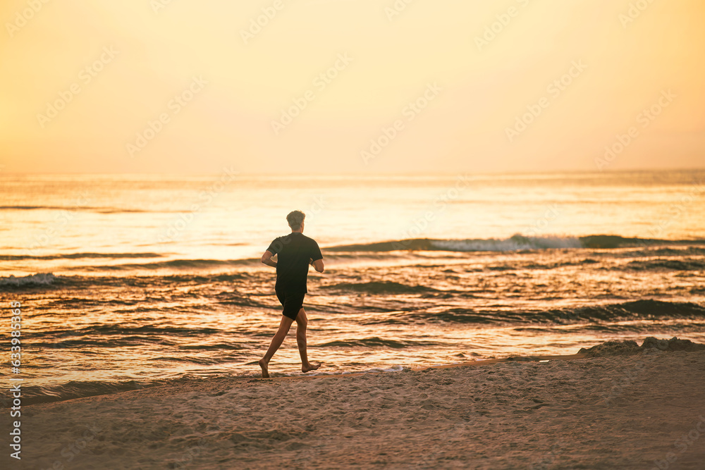 Silhouette of a young man running during sunset. Running on the ocean beach.