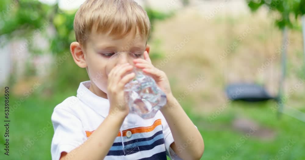 Thirsty child drinking water from glass in the garden outdoors in sunny day Thirsty child drinking water from glass in the garden outdoors in sunny day