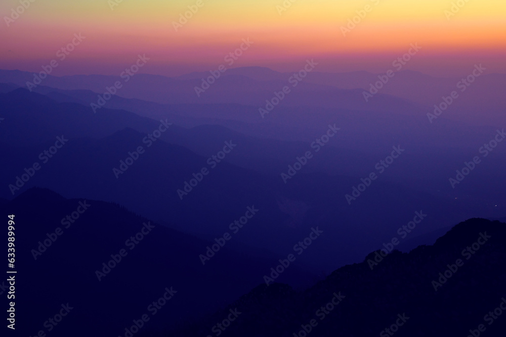 Silhouettes of mountain ranges in the evening haze
