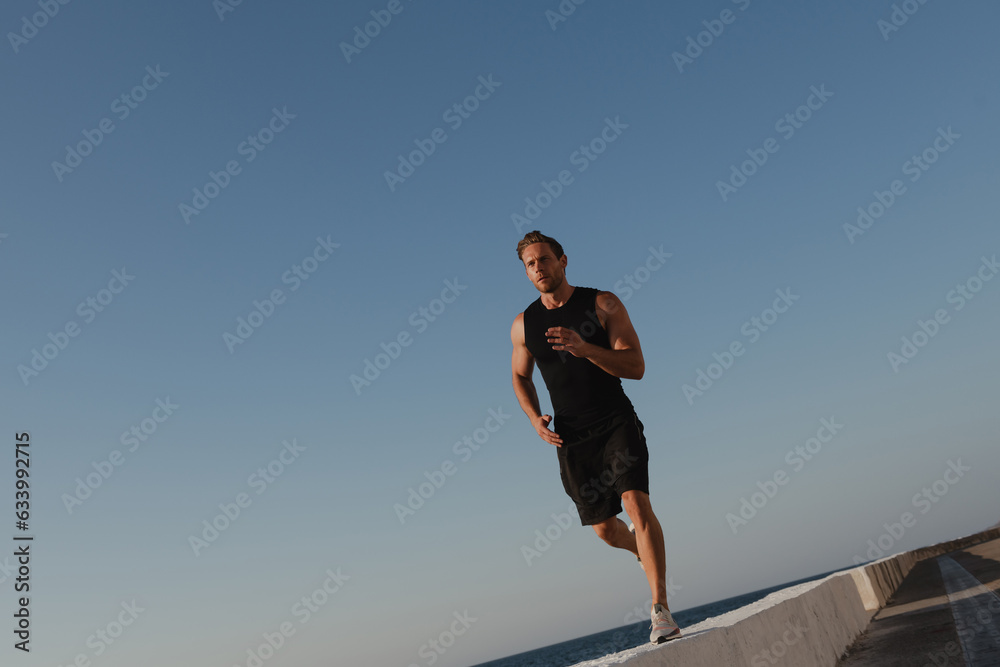 Confident young man in sports clothing enjoying his morning jog outdoors Confident young man in sports clothing enjoying his morning jog outdoors