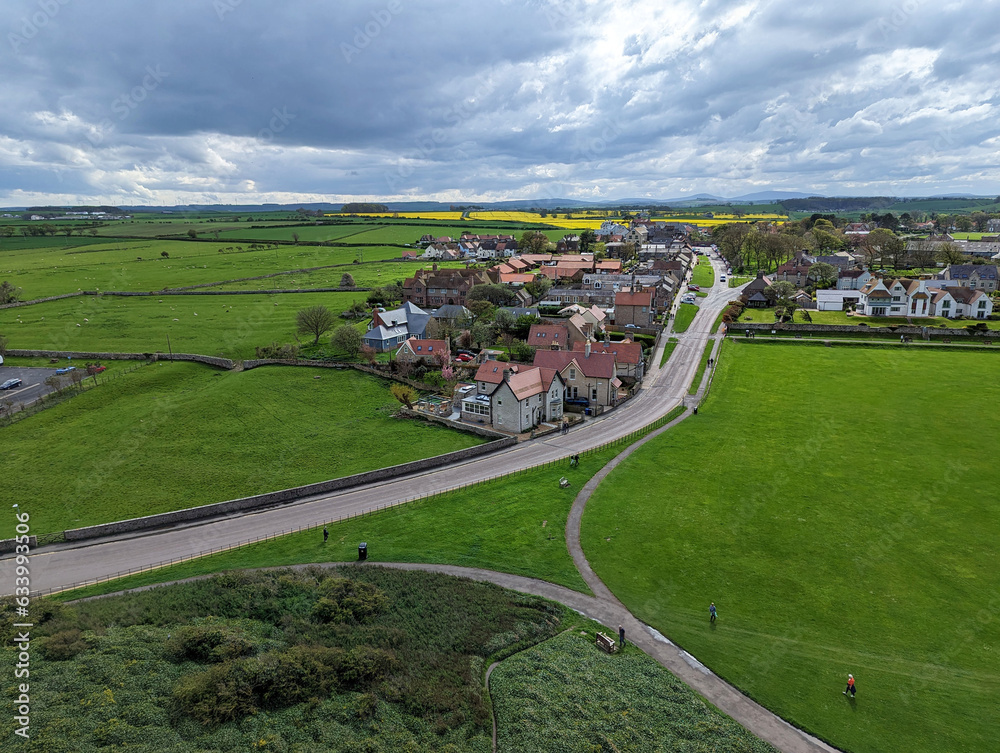 A view across the lush spring green fields to Bamburgh village in Northumberland, England, UK.